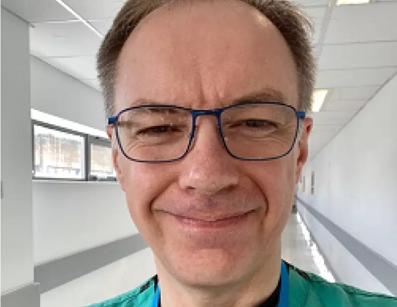 Professor Stefan Marciniak is wearing glasses and green scrubs. He smiles. 